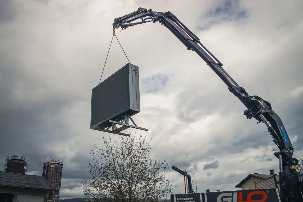 Ein ausgefahrener Kran von einem LKW hebt einen LED Wall an seinen Platz