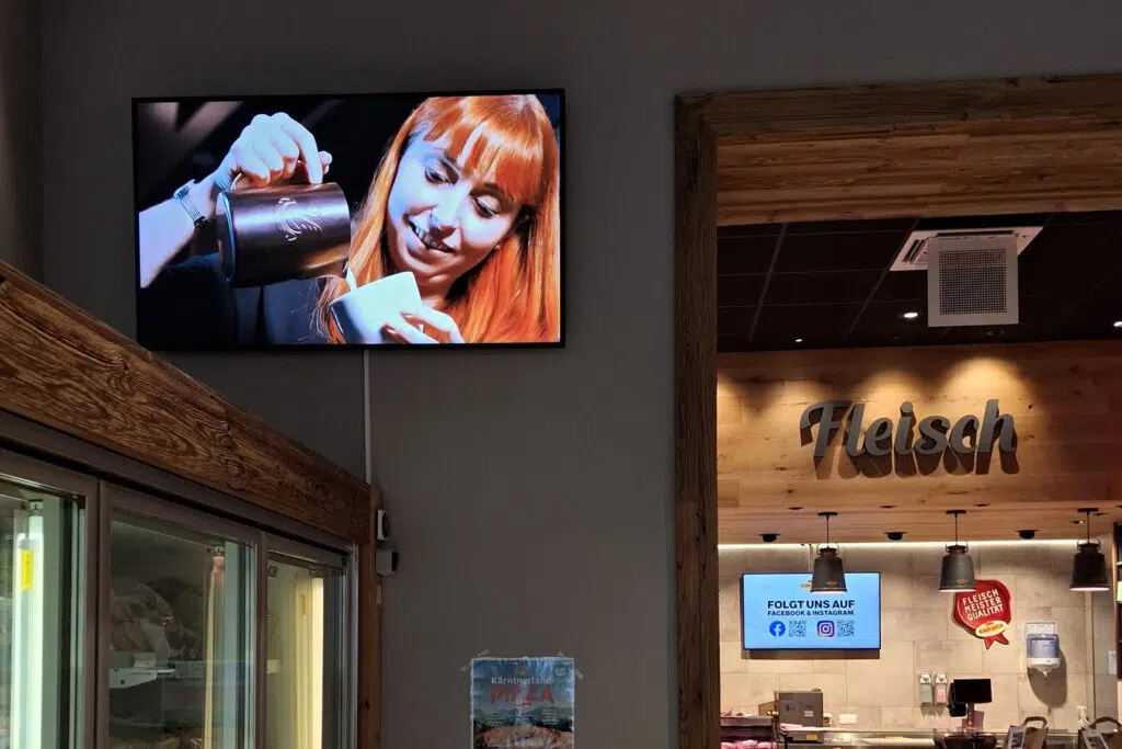 digital-signage-monitore-im-shop-kaerntner-milch-genussmaierei-wallerie Bildschirm hängend auf einer Wand in einem Geschäft