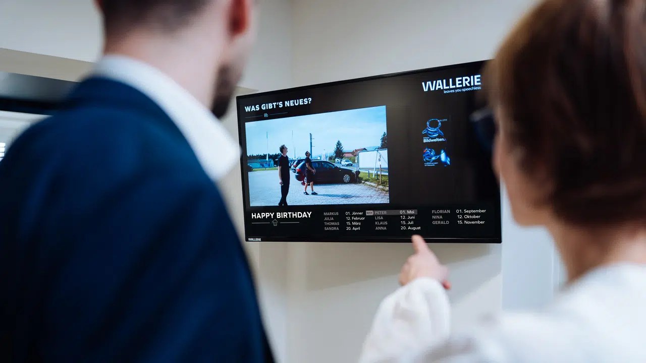 digital-signage-mitarbeiter-infosystem-wallerie 2 Personen von einem Screen im Büro