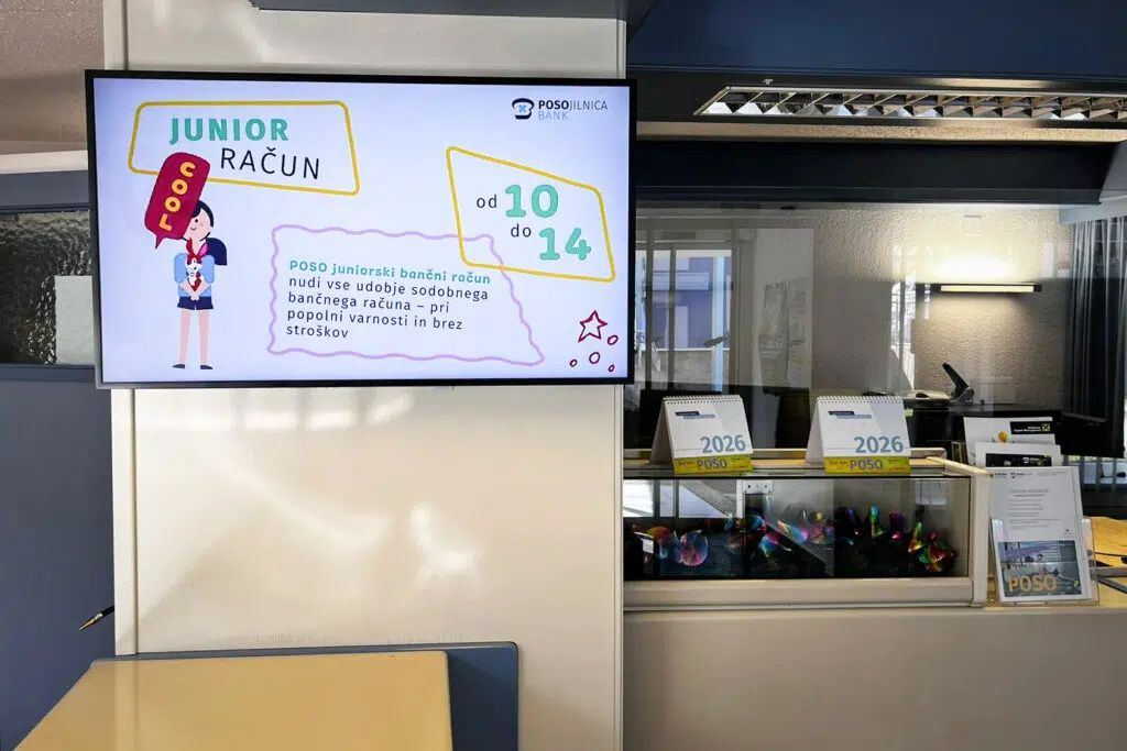 poso-bank-managed-digital-signage-system-by-wallerie-02 Digital Signage Screen in einer Filiale der Posojilnica Bank: Werbung für das Junior-Konto für Kinder von 10 bis 14 Jahren, mit bunter Grafik und slowenischem Text.